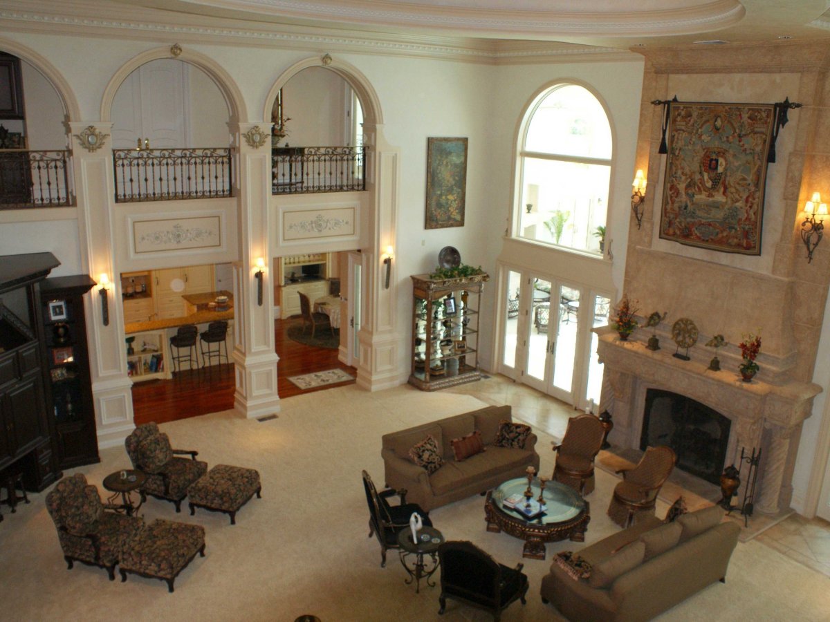 this-is-the-upstairs-view-of-the-living-room-which-has-large-windows-arched-entrance-ways-and-a-fireplace